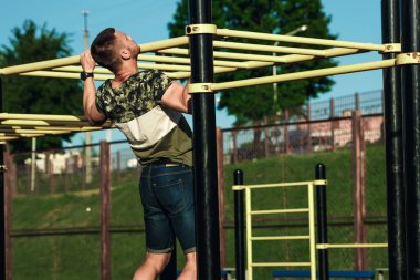 Genç bir adam kendini yukarı çeker spor zemin, bir atlet, şehirde eğitim açık havada.