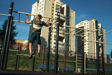 Genç bir adam kendini yukarı çeker spor zemin, bir atlet, şehirde eğitim açık havada.