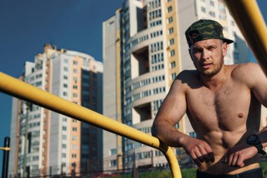 Stadyumdaki düzensiz barlarda egzersiz yapan genç adam, sporcu, şehirdeki açık hava eğitimi.