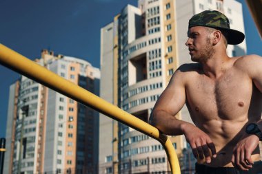 Stadyumdaki düzensiz barlarda egzersiz yapan genç adam, sporcu, şehirdeki açık hava eğitimi.
