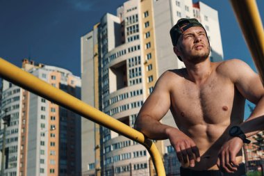 Stadyumdaki düzensiz barlarda egzersiz yapan genç adam, sporcu, şehirdeki açık hava eğitimi.