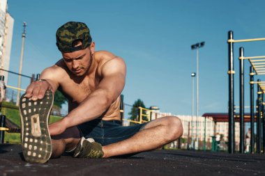 Genç bir adam bir spor alanı, bir atlet, şehirde eğitim açık havada uzanır.