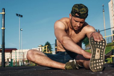 Genç bir adam bir spor alanı, bir atlet, şehirde eğitim açık havada uzanır.