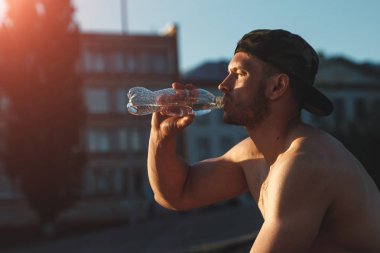 Genç bir adam bir egzersiz, içme suyu, bir atlet, şehirde eğitim açık havada sonra dinleniyor