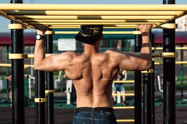 Genç bir adam kendini yukarı çeker spor zemin, bir atlet, şehirde eğitim açık havada.