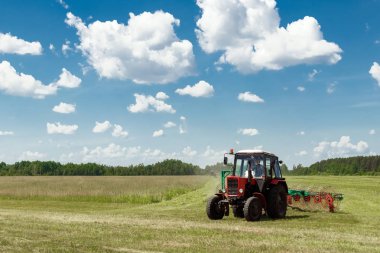 Tarım makineleri, mavi gökyüzü karşı bir alanda ot toplama bir traktör. Hasat saman, hasat çimen. Sezon hasat, çim, tarım arazisi.