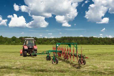 Tarım makineleri, mavi gökyüzü karşı bir alanda ot toplama bir traktör. Hasat saman, hasat çimen. Sezon hasat, çim, tarım arazisi.