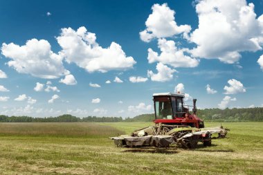 Tarım makineleri, mavi gökyüzü karşı bir alanda çim biçme hasat. Hasat saman, hasat çimen. Sezon hasat, çim, tarım arazisi.