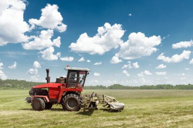 Tarım makineleri, mavi gökyüzü karşı bir alanda çim biçme hasat. Hasat saman, hasat çimen. Sezon hasat, çim, tarım arazisi.