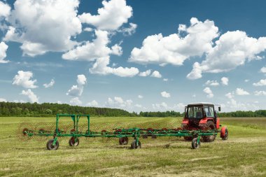 Tarım makineleri, mavi gökyüzü karşı bir alanda ot toplama bir traktör. Hasat saman, hasat çimen. Sezon hasat, çim, tarım arazisi.