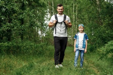 Bir sırt çantası, bir baba ve oğlu sırasında yürüyüş bir yürüyüş üzerinde olan bir adam ormanda yürür. Aile hayatı, Aile, çocuk yetiştirme ile eğlence.