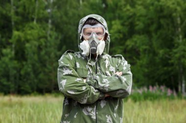 Bir adam bir maske ve gözlük ve bir kamuflaj doğa arka planı uygun. Kimyasal orduları.