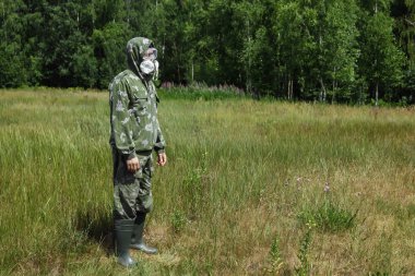 Bir adam bir maske ve gözlük ve bir kamuflaj doğa arka planı uygun. Kimyasal orduları.