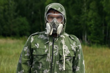 Bir adam bir maske ve gözlük ve bir kamuflaj doğa arka planı uygun. Kimyasal orduları.