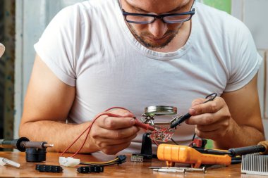 Adam uzaktan kumanda microcircuit. Çalışma alanı havya, microcircuit, Büyüteç Camı, Büyüteç Camı, ölçme aletleri ile. Elektronik onarım, ana.