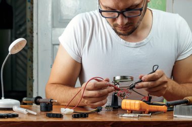 Adam uzaktan kumanda microcircuit. Çalışma alanı havya, microcircuit, Büyüteç Camı, Büyüteç Camı, ölçme aletleri ile. Elektronik onarım, ana.