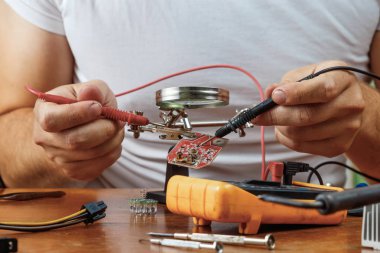 Adam uzaktan kumanda microcircuit. Çalışma alanı havya, microcircuit, Büyüteç Camı, Büyüteç Camı, ölçme aletleri ile. Elektronik onarım, ana.