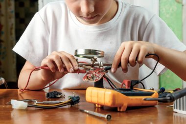 Çocuk remotiruet microcircuit. Çalışma alanı havya, microcircuit, Büyüteç Camı, Büyüteç Camı, ölçme aletleri ile. Meslek seçimi.