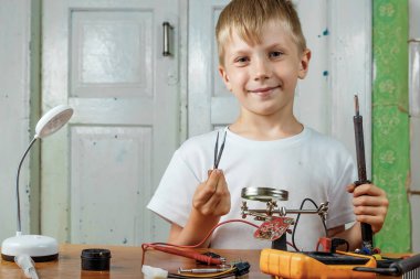 Çocuk remotiruet microcircuit. Çalışma alanı havya, microcircuit, Büyüteç Camı, Büyüteç Camı, ölçme aletleri ile. Meslek seçimi.