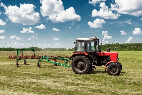 Tarım makineleri, mavi gökyüzü karşı bir alanda ot toplama bir traktör. Hasat saman, hasat çimen. Sezon hasat, çim, tarım arazisi.