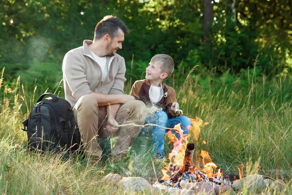 Baba ve oğul yeşil doğanın bir arka plan karşı ateşle. Yürüyüş, zaman aile, Aile hayatı, açık rekreasyon.