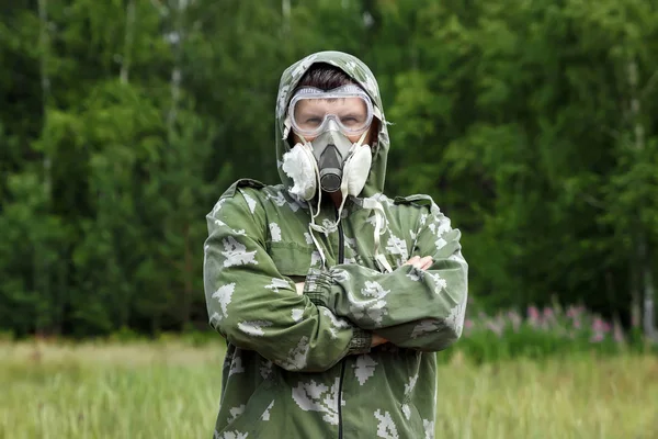 Bir adam bir maske ve gözlük ve bir kamuflaj doğa arka planı uygun. Kimyasal orduları.