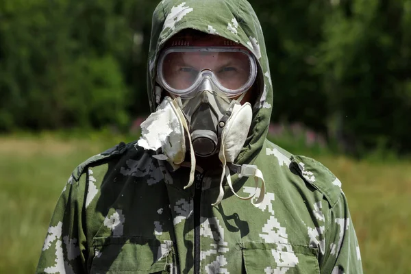 Bir adam bir maske ve gözlük ve bir kamuflaj doğa arka planı uygun. Kimyasal orduları.