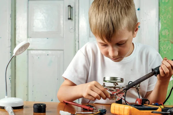 The child remotiruet microcircuit. Workplace with soldering iron, microcircuit, magnifying glass, magnifying glass, measuring instruments. Choice of profession.