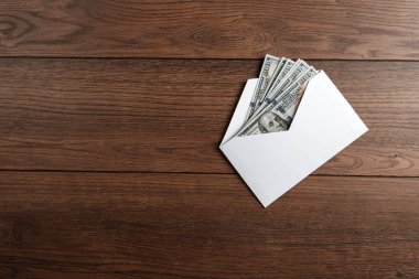 Bize dolar ahşap bir masa üzerinde beyaz bir zarf içinde. Gelir, ikramiye ya da rüşvet kavramı. Yolsuzluk, maaş, ikramiye.