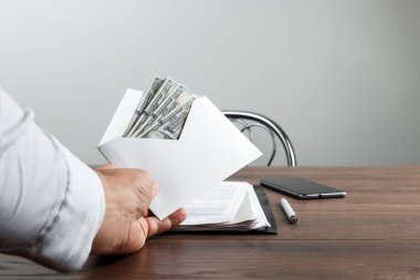 Bir adamın elini bir zarf ve bize dolar. Rüşvet, yolsuzluk iş kavramı olarak beyaz bir zarf sunan bir girişimci.