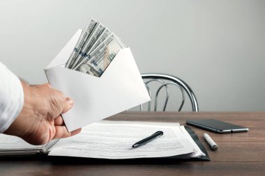 Bir adamın elini bir zarf ve bize dolar. Rüşvet, yolsuzluk iş kavramı olarak beyaz bir zarf sunan bir girişimci.