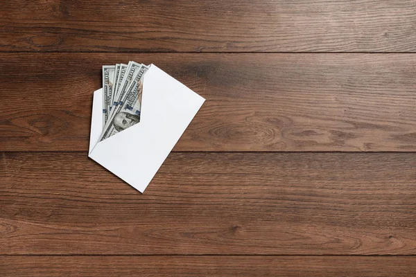 Bize dolar ahşap bir masa üzerinde beyaz bir zarf içinde. Gelir, ikramiye ya da rüşvet kavramı. Yolsuzluk, maaş, ikramiye.