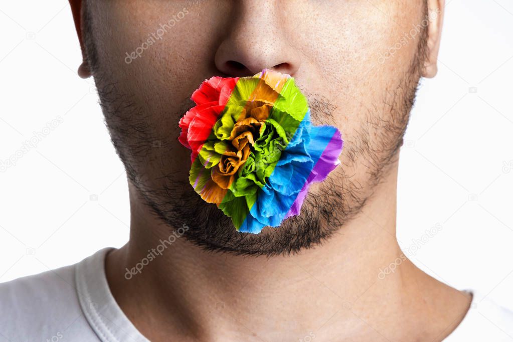 The face of a man with a flower in his mouth, painted in the colors of LGBT people. The concept of same-sex relationships, same-sex marriages, the LGBT movement.