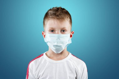 Küçük çocuk, bir çocuk mavi bir arka plan üzerinde tıbbi maskeli. Bir salgın, grip, hastalık, aşı koruma kavramı.