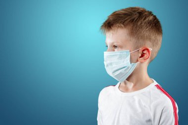 Küçük çocuk, bir çocuk mavi bir arka plan üzerinde tıbbi maskeli. Bir salgın, grip, hastalık, aşı koruma kavramı.