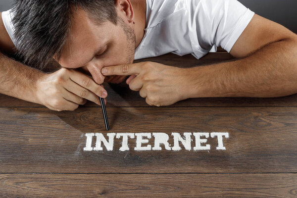 Internet addiction. A man sniffs a powder in the form of an inscription online. The concept of dependence on modern technology, drug addiction.