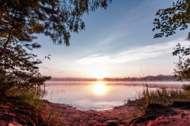 Güzel, pembe mor şafak göl üzerinde. Sis göl, Güneş, çok yoğun sis, şafak, göl üzerinde mavi gökyüzü ışınları üzerinde sabah geliyor, orman suda yansıtır.