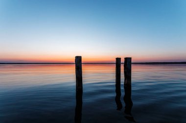 Güzel, pembe günbatımı su ön planda dokulu bir giriş ile.