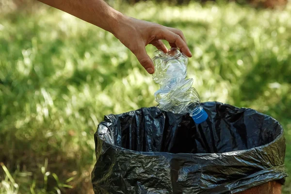 Close up hand throwing empty plastic bottle into the trash