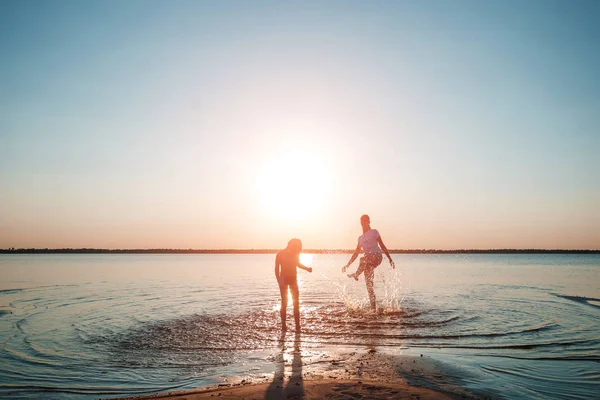 Family on the lake against a beautiful sunset. A happy life, happiness