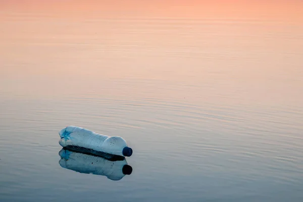 Concept of pollution, creative background. A plastic bottle floating in the ocean, non-decomposable plastic, pollution of the environment.