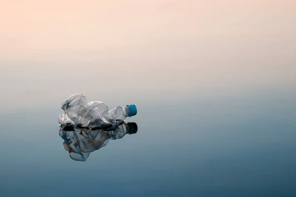 Concept of pollution, creative background. A plastic bottle floating in the ocean, non-decomposable plastic, pollution of the environment.