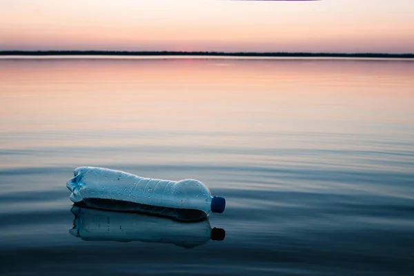 Concept of pollution, creative background. A plastic bottle floating in the ocean, non-decomposable plastic, pollution of the environment.