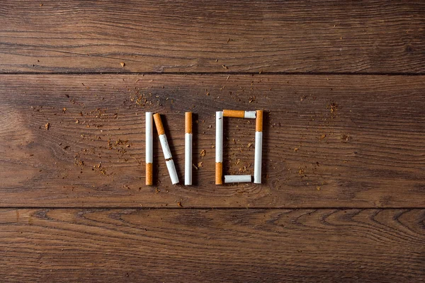 Fondo creativo, la palabra no se compone de cigarrillos sobre un fondo de madera marrón. El concepto de fumar mata venenos de nicotina. Copiar espacio . — Foto de Stock