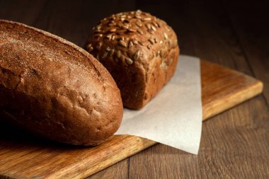 Yaratıcı arka plan, fırından yeni çıkmış çavdar ekmeği bir ahşap kesme tahtası üzerinde düz yatıyordu, dilimlenmiş Kopyala alanı. Taze pasta, siyah ekmek kavramı.