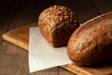 Yaratıcı arka plan, fırından yeni çıkmış çavdar ekmeği bir ahşap kesme tahtası üzerinde düz yatıyordu, dilimlenmiş Kopyala alanı. Taze pasta, siyah ekmek kavramı.