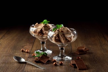 Ev yapımı çikolatalı dondurma nane yaprakları, ahşap bir masa üzerinde bir cam kabın içinde çikolata serpilir. çikolata parçaları, fındık. Seçici odak, kopya alanı.
