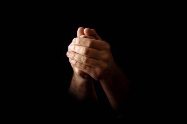 Men's hands in prayer on a black background. The concept of faith, prayer, mourning, forgiveness, confession. clipart