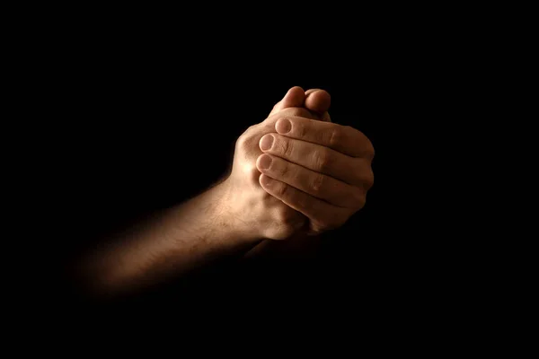 Men\'s hands in prayer on a black background. The concept of faith, prayer, mourning, forgiveness, confession.