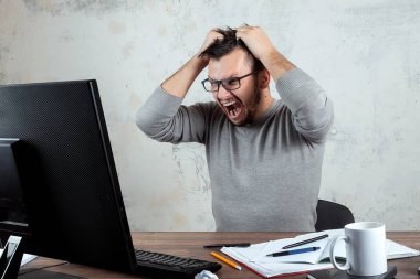 Kızgın Adam, ofiste bir masada oturan ve öfkeyle çığlık atan bir adam, ağzı tamamen açık, bir sürü iş var. Ofis işi kavramı, olumsuz duygular, öfke. Kopyalama alanı.